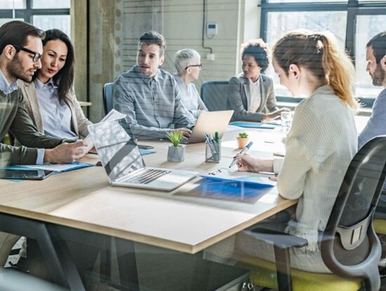 Seven people sitting at a table having a discussion in a conference room